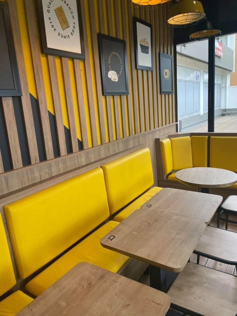 Salle d'un snack, banquettes jaunes et tables en bois