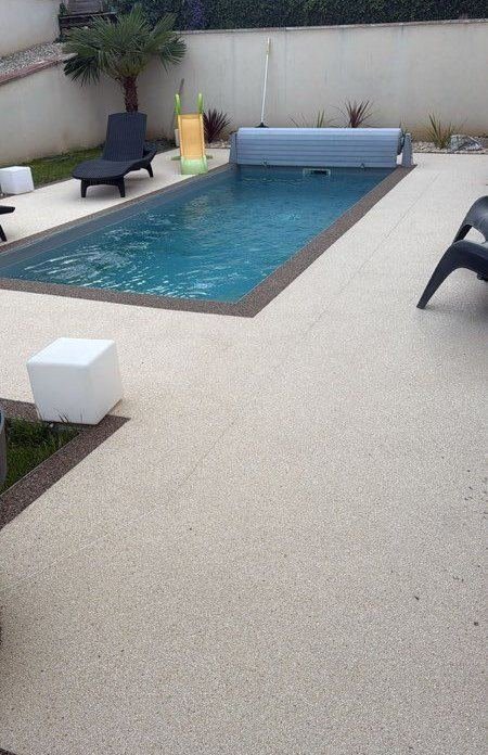Plage de piscine en moquette de pierre claire, bordure plus foncée autour du bassin