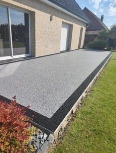 Terrasse en moquette de pierre grise le long d'une maison, bordure foncée