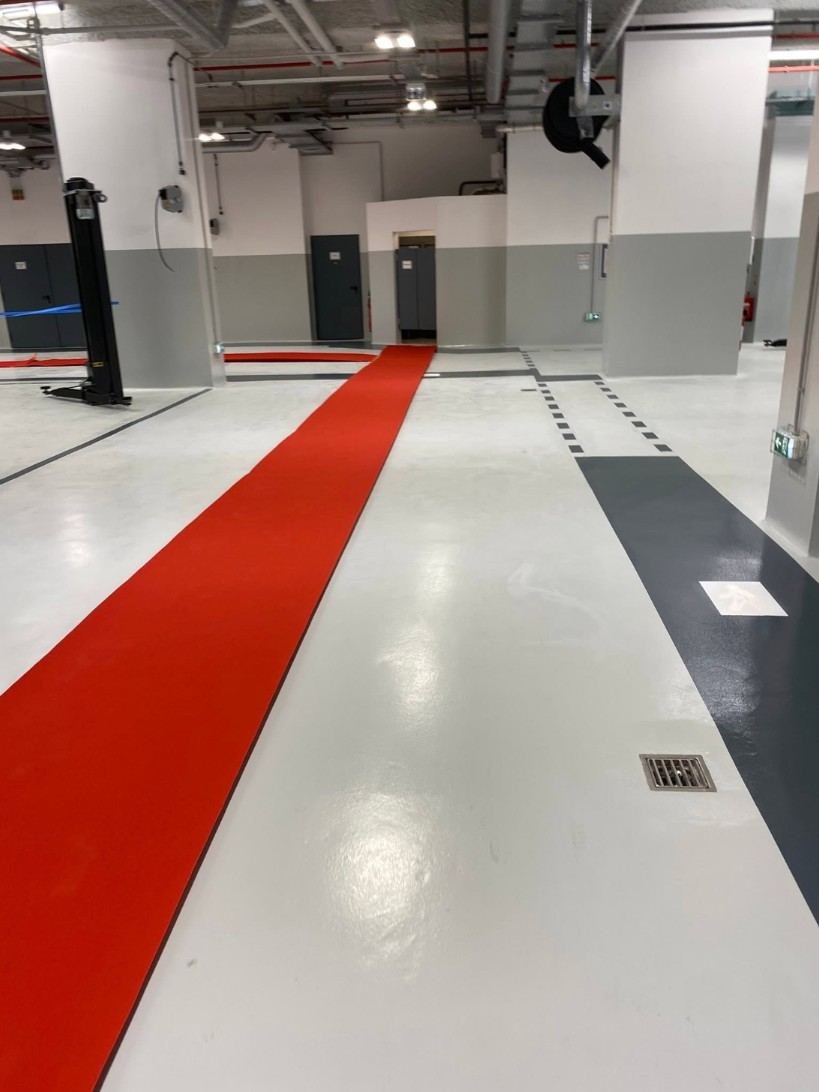 Atelier automobile en résine claire, bandes anthracite et tapis rouge déroulé