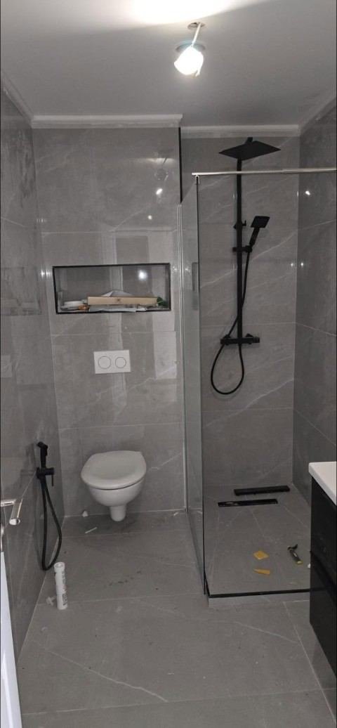 Salle de bains en grès gris, douche à l'italienne et paroi vitrée